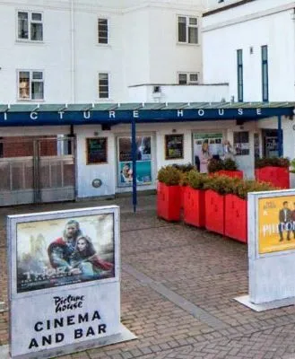 Exterior of Picture House Cinema in Stratford-upon-Avon, showing movie posters and signs for the cinema and bar.