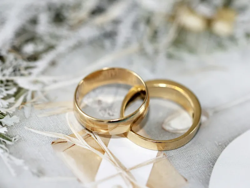 Two gold wedding rings placed on a decorative surface