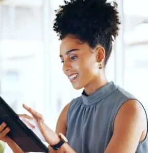 Woman smiling while using a tablet in a bright office setting