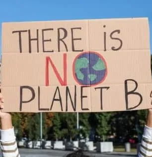 Person holding a cardboard sign that says 'There is No Planet B' with an illustration of Earth as the letter O.