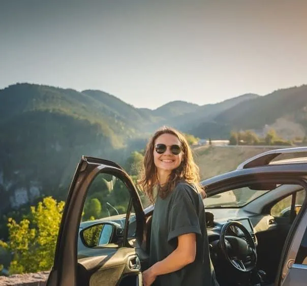 Woman standing by car with mountains in the background