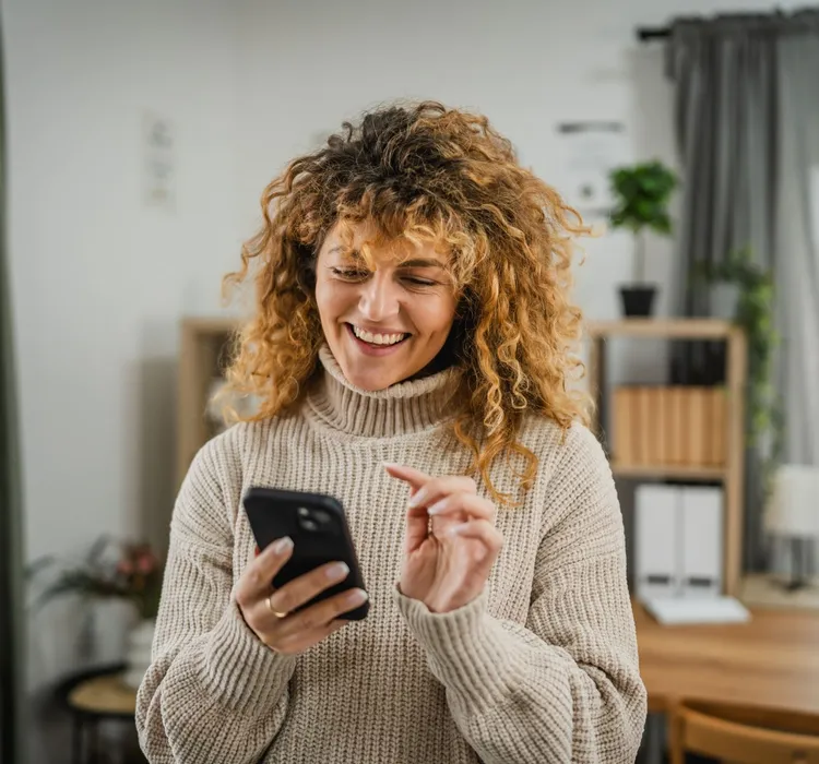 Smiling woman using smartphone at home