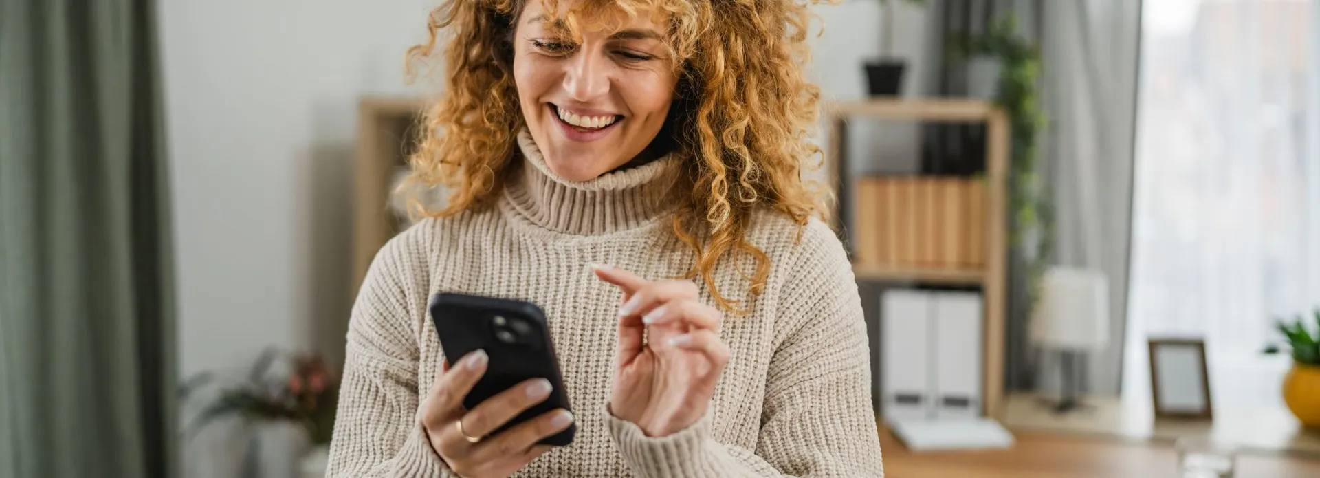 Smiling woman using smartphone at home
