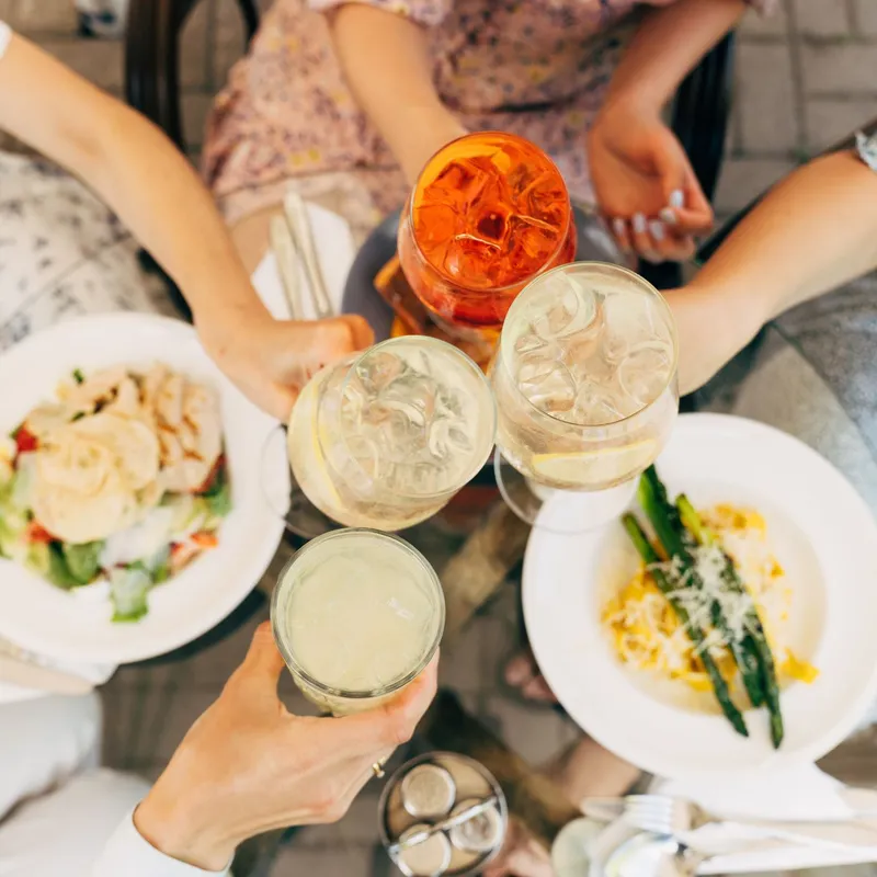 Group of friends toasting drinks over a meal at an outdoor table