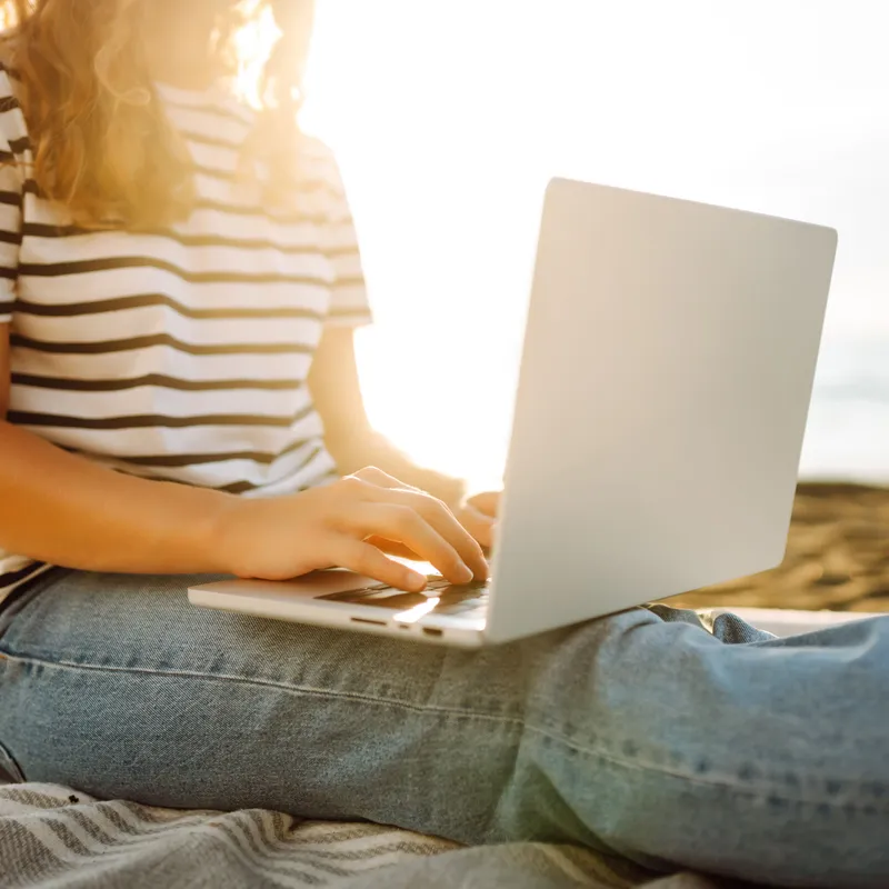 Person sitting on beach using a laptop