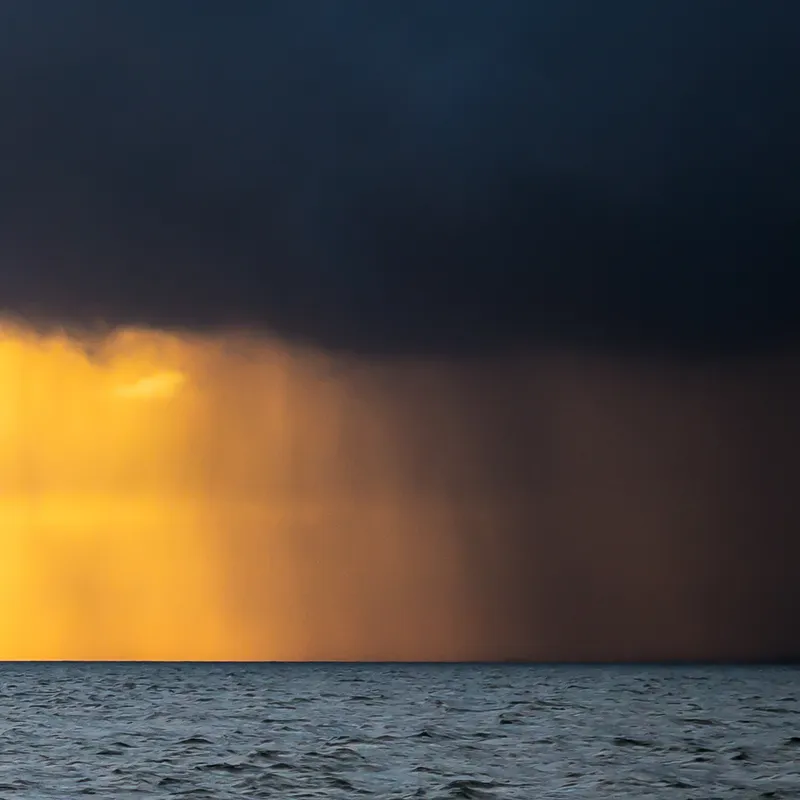 Dark storm clouds over the sea with golden sunlight breaking through