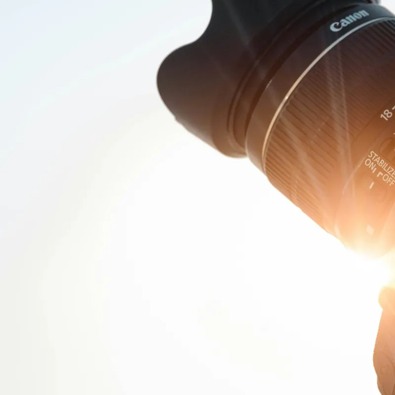 Close-up of a Canon camera lens with sunlight flare
