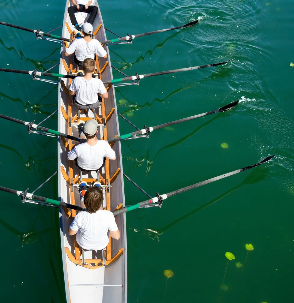 Aerial view of a rowing team in a boat on green water