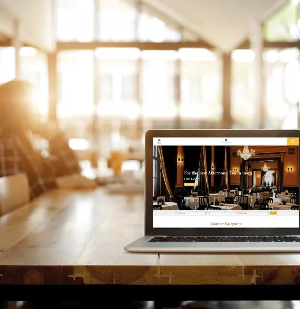Laptop on table displaying restaurant booking website in bright, modern cafe setting