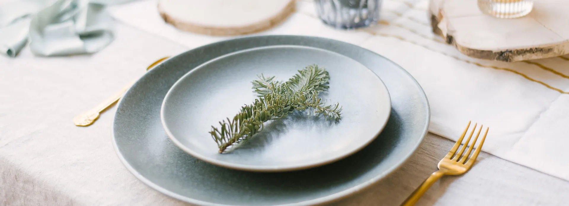 Elegant holiday table setting with pine branch on plate