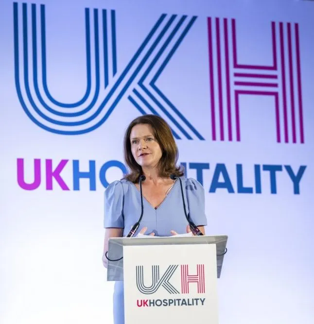 Kate Nicholls, Chief Executive of UKHospitality, speaking at a lectern in front of the UKHospitality logo.