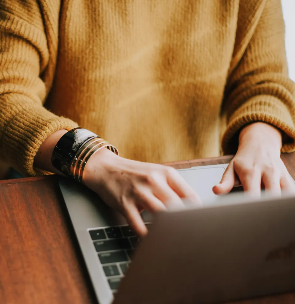 Lady typing on laptop with yellow top