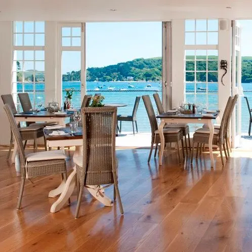 Restaurant with open doors overlooking a scenic waterfront and hills