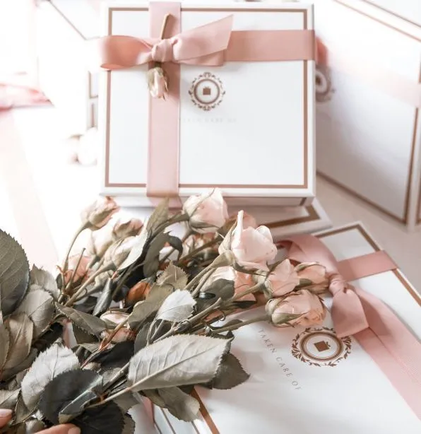 Elegant gift boxes tied with pink ribbons and a bouquet of pale pink roses