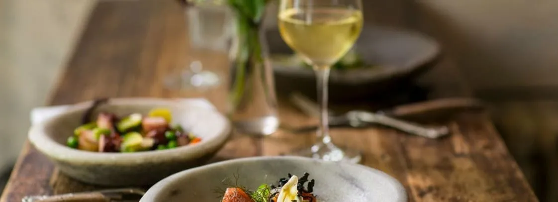 A gourmet meal served in a rustic setting with a glass of white wine