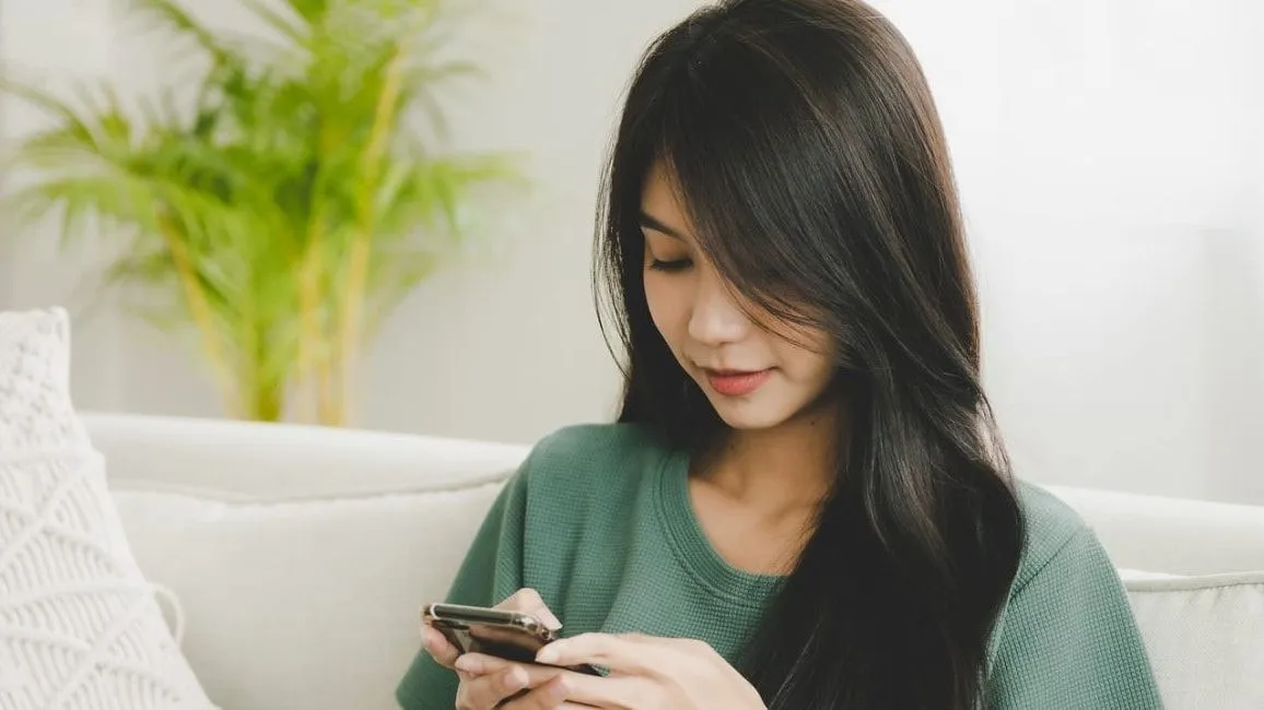 Woman sitting on a couch looking at her smartphone