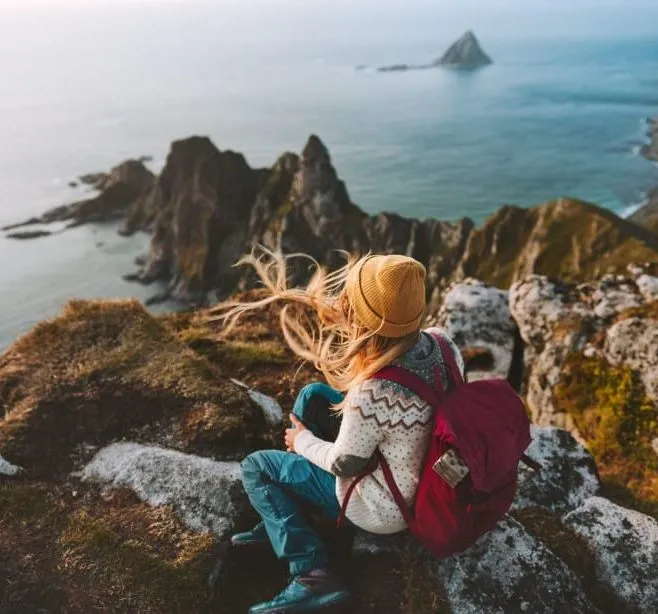 Woman sitting on a mountain cliff overlooking the sea with a small island in the distance