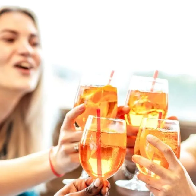 Group of friends clinking glasses in a toast while sitting together at a table.
