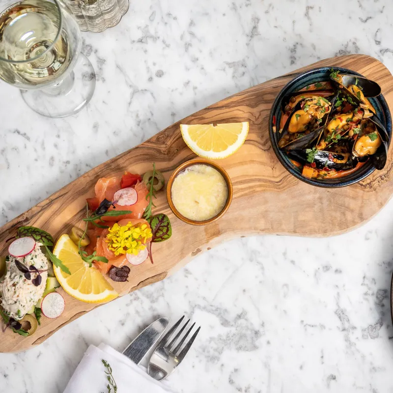 Elegant seafood appetizer platter on a wooden board with a glass of white wine