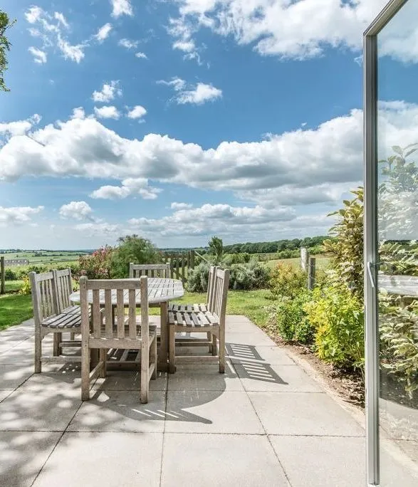 Patio at Glenside Cottage with wooden outdoor dining set and open countryside views