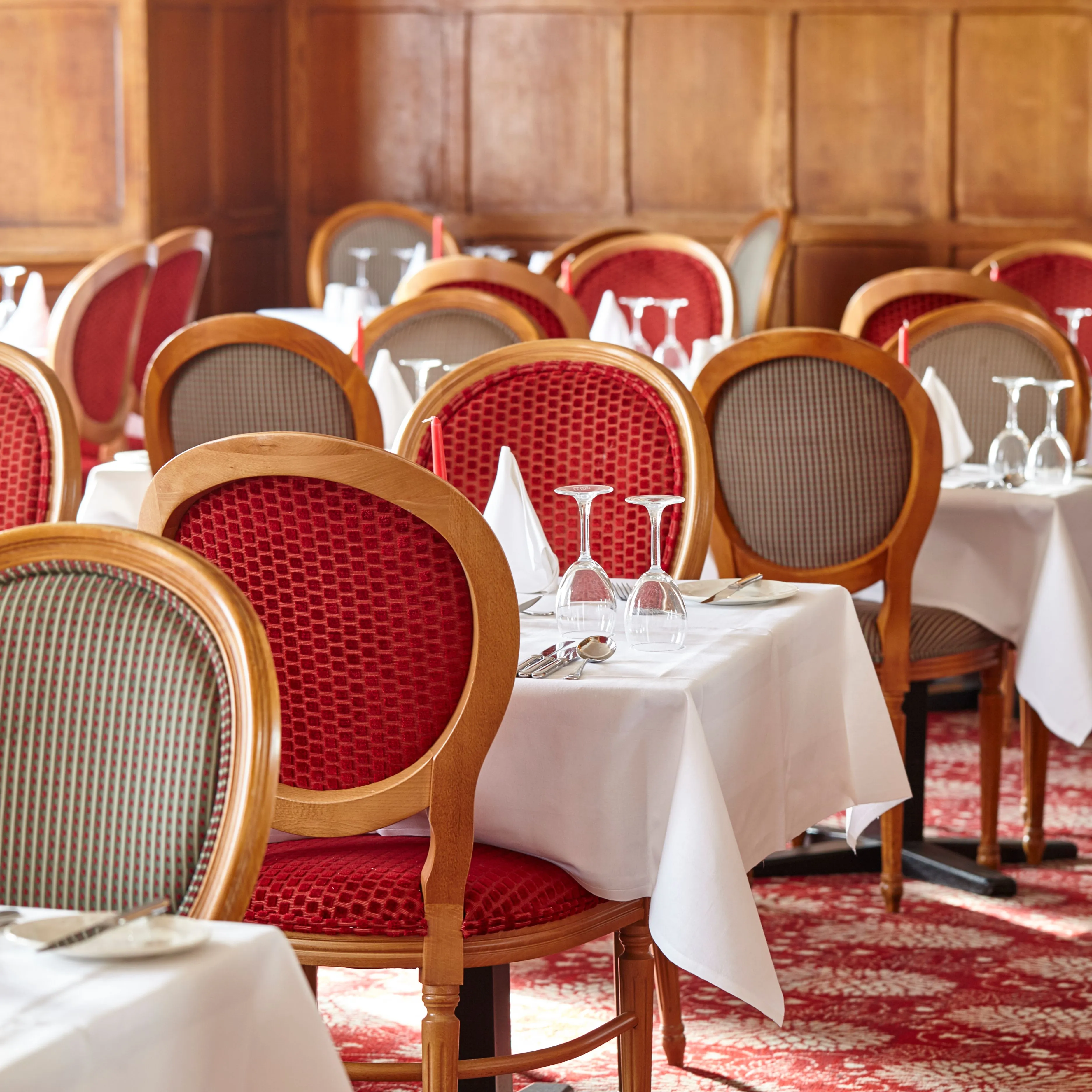 Elegant hotel dining room with red upholstered chairs, white tablecloths and wood-panelled walls at the Royal Hotel in Sidmouth.
