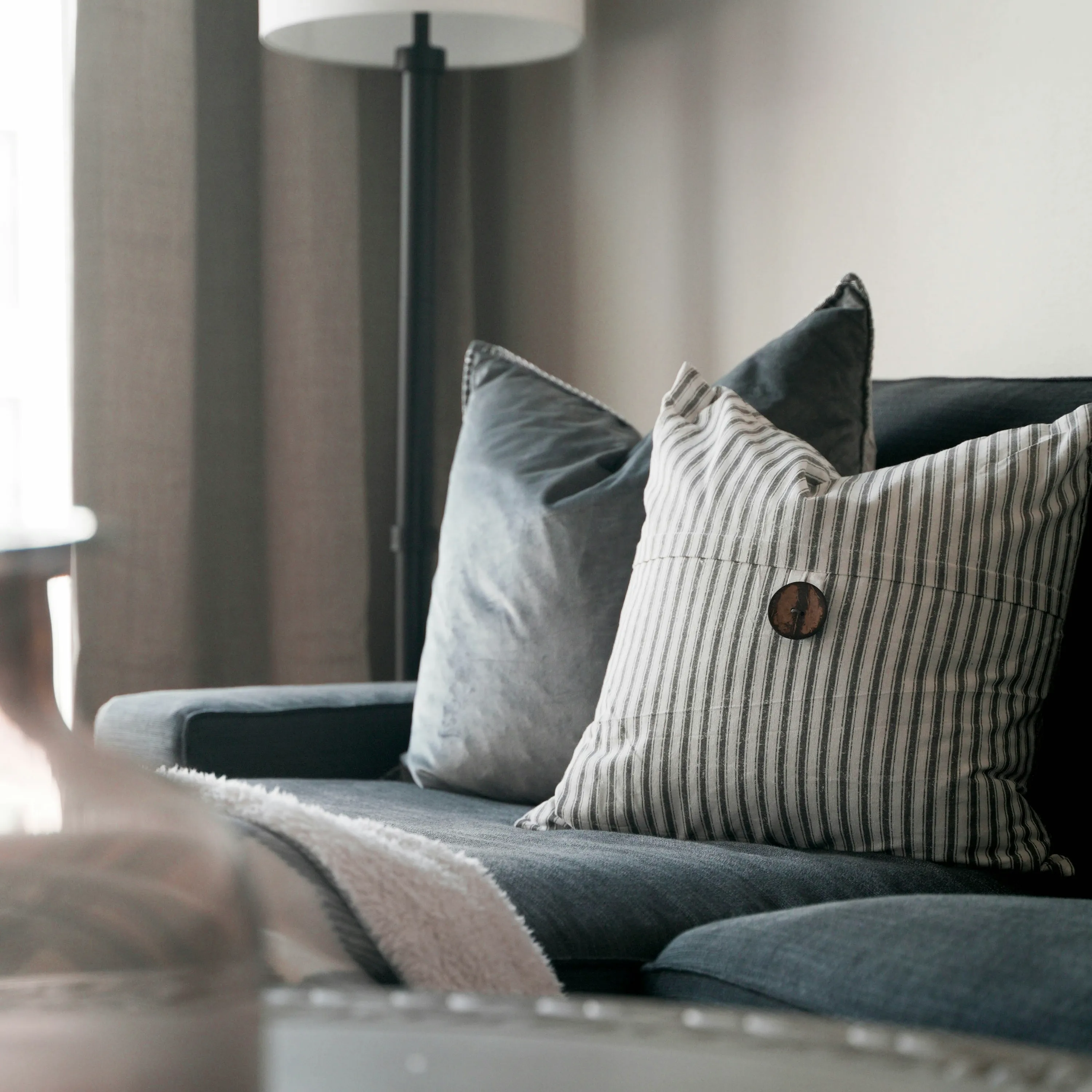 Grey upholstered sofa with soft cushions and a floor lamp in a calm, modern living room