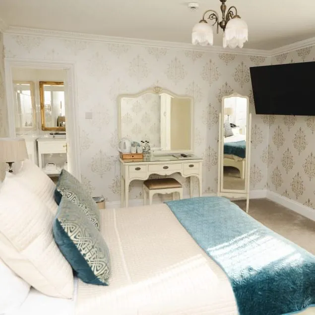 Elegant bedroom at Stallingborough Grange with a dressing table, wall-mounted television and gold curtains