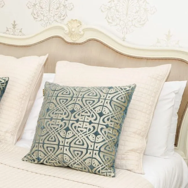 Elegant cream bedroom with an upholstered headboard, patterned blue cushions and matching bedside lamps.