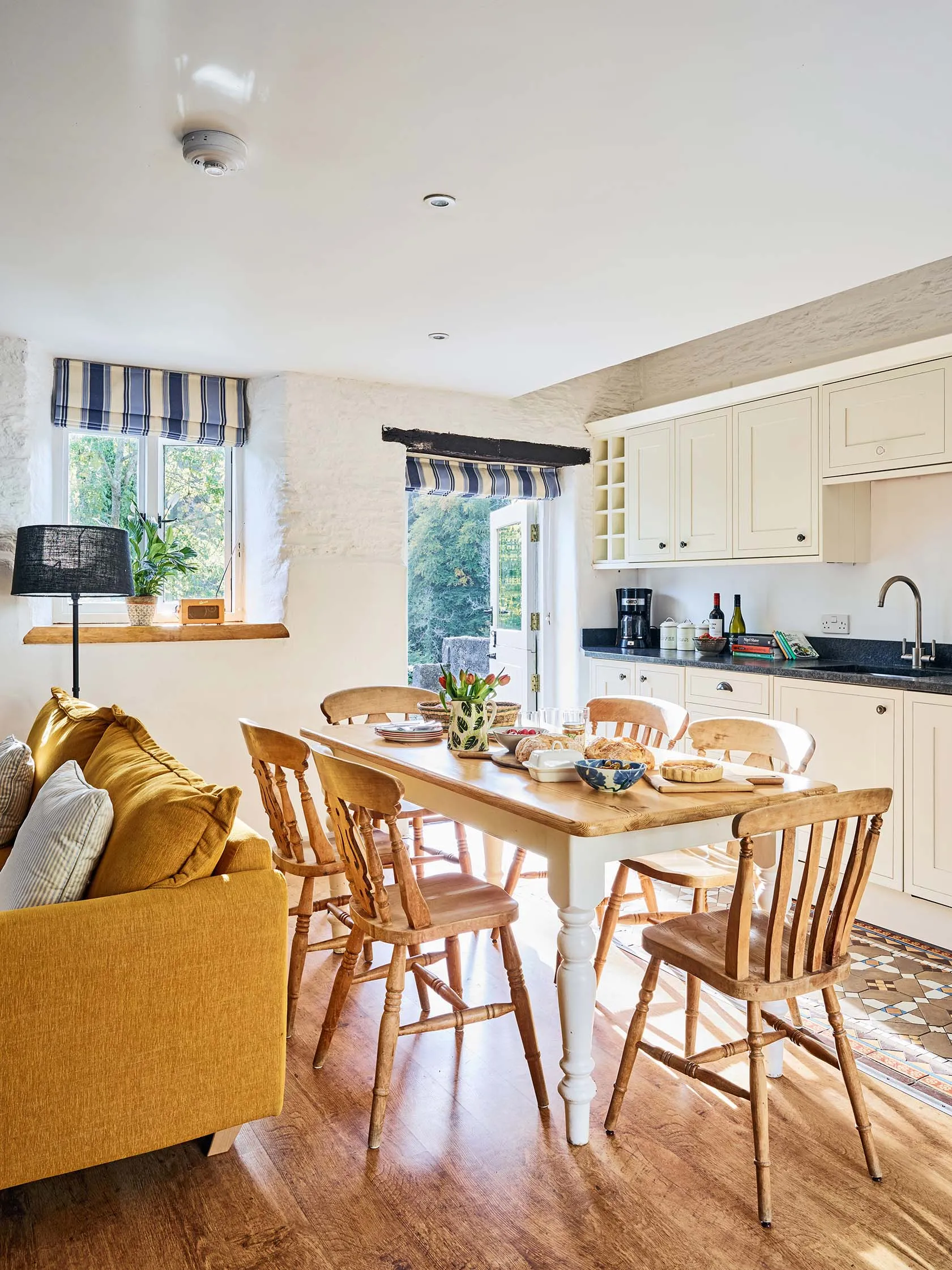 Bright kitchen and dining area in The Stables at Flear Farm Cottages, with cream cabinets, wooden furniture, and patio doors to outside.