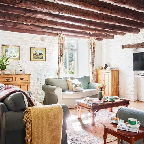 Portrait view of the Granary’s living room at Flear Farm Cottages, with exposed beams, soft seating, rustic furnishings, and sunlight streaming in.