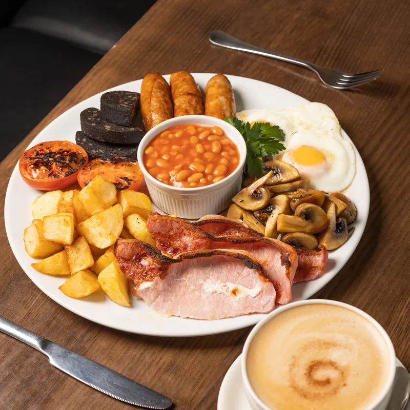 Full English breakfast with bacon, sausages, fried egg, black pudding, beans, mushrooms, grilled tomatoes, potatoes and coffee