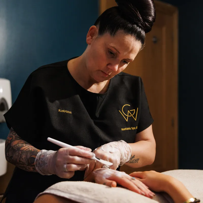 Spa therapist performing a professional treatment on a client's abdomen in a softly lit treatment room.
