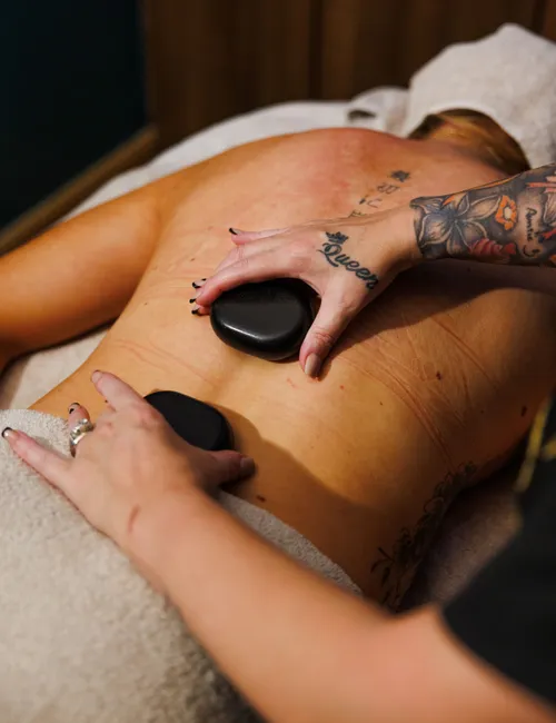 Massage therapist placing hot stones on a client’s back during a spa treatment
