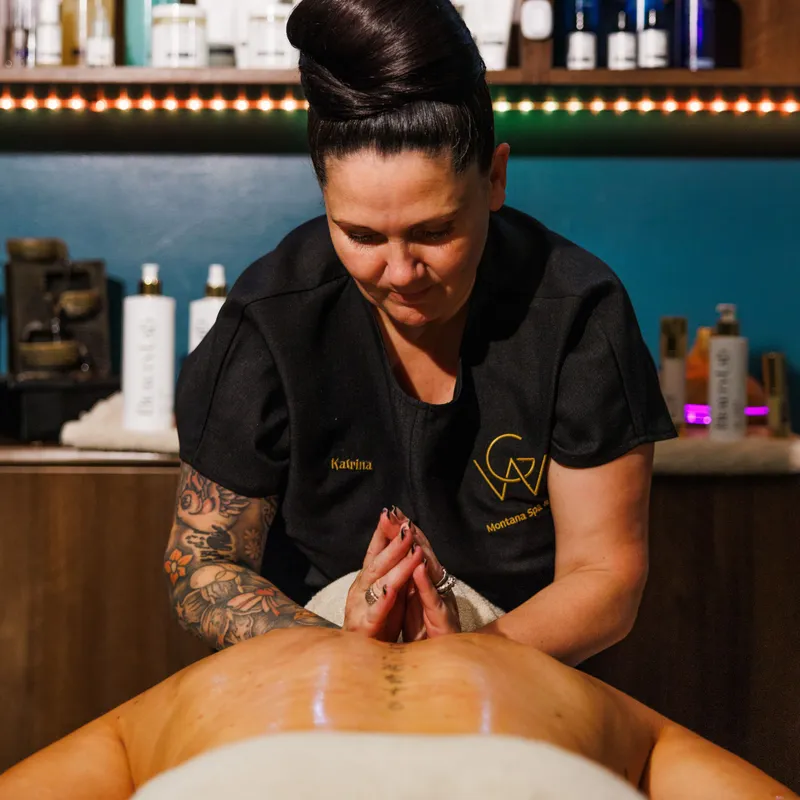 Massage therapist giving a back massage in a warmly lit spa treatment room