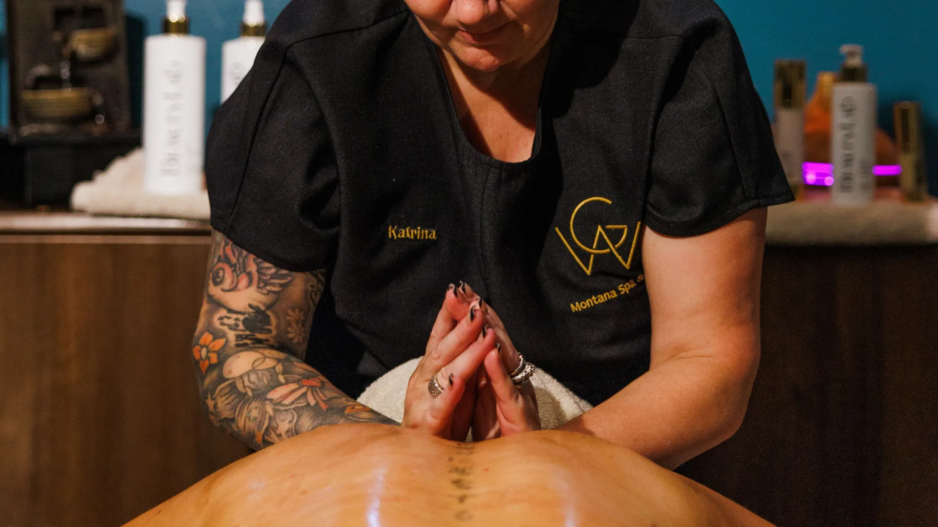 Massage therapist giving a back massage in a warmly lit spa treatment room