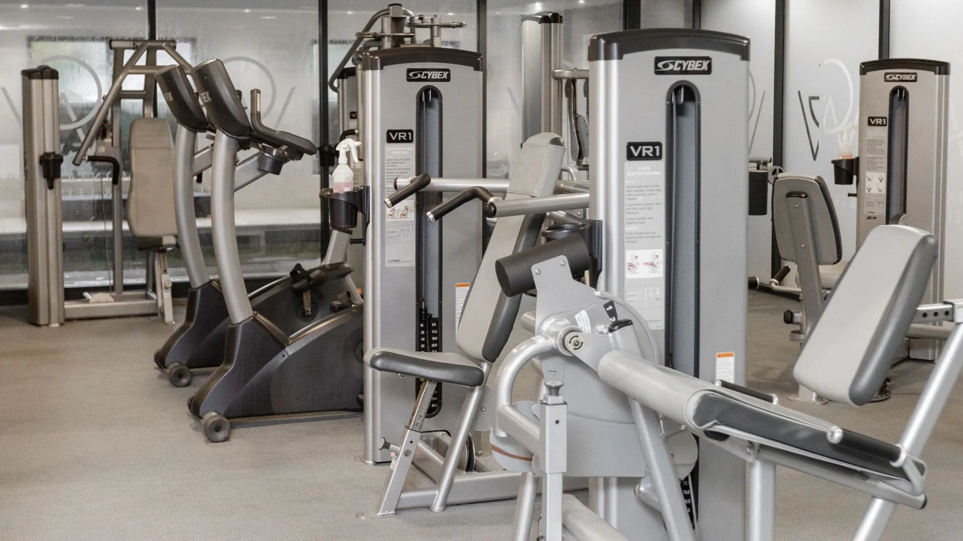 Modern gym interior with strength-training machines and elliptical cross trainers.