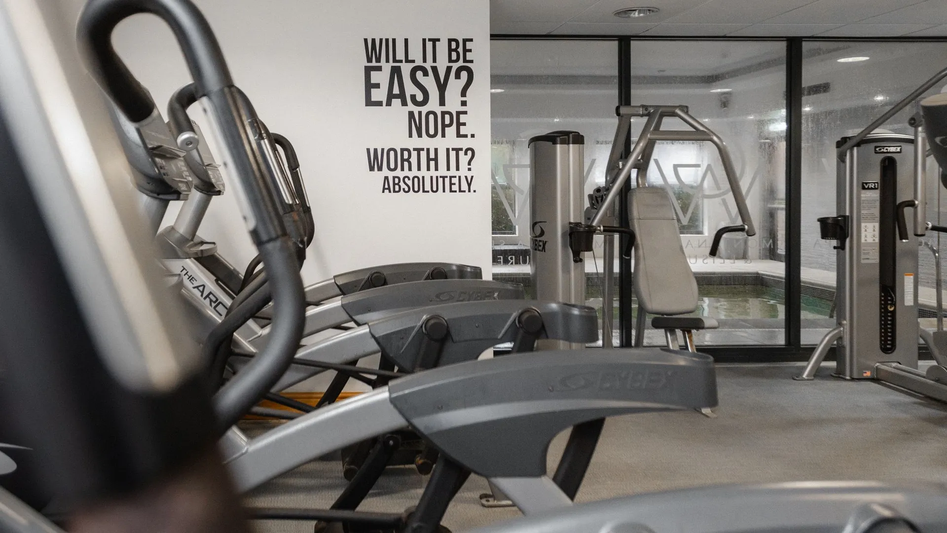 Modern gym interior with exercise machines and a motivational wall quote