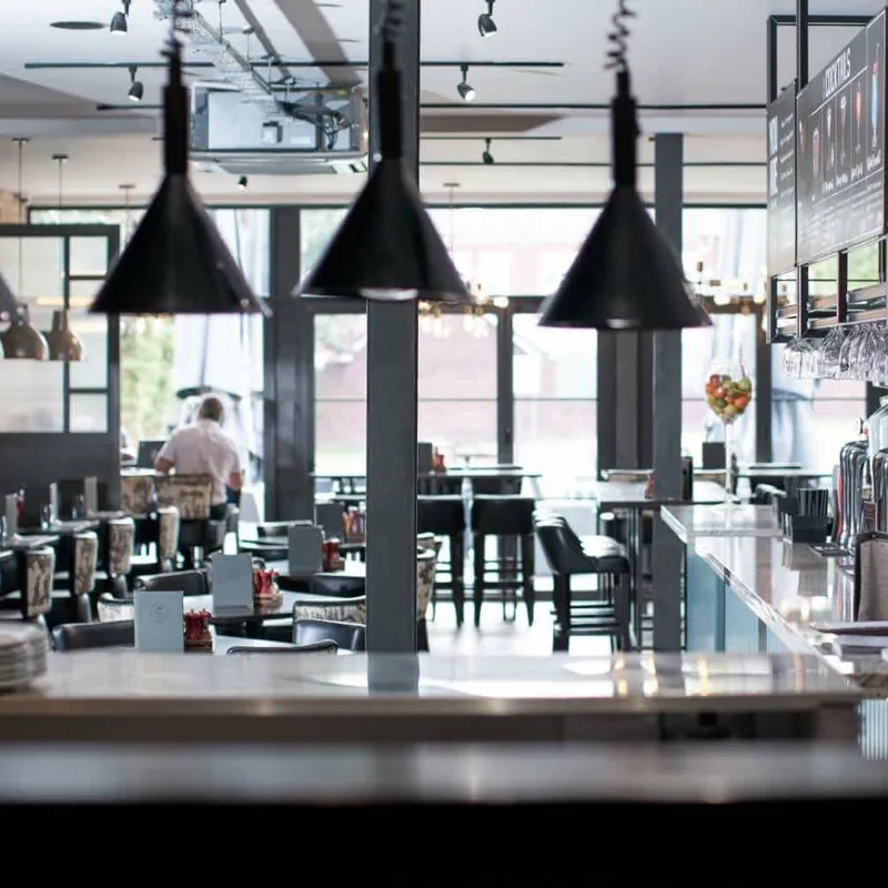 Modern hotel restaurant and bar with black pendant lights, dining tables and beer taps