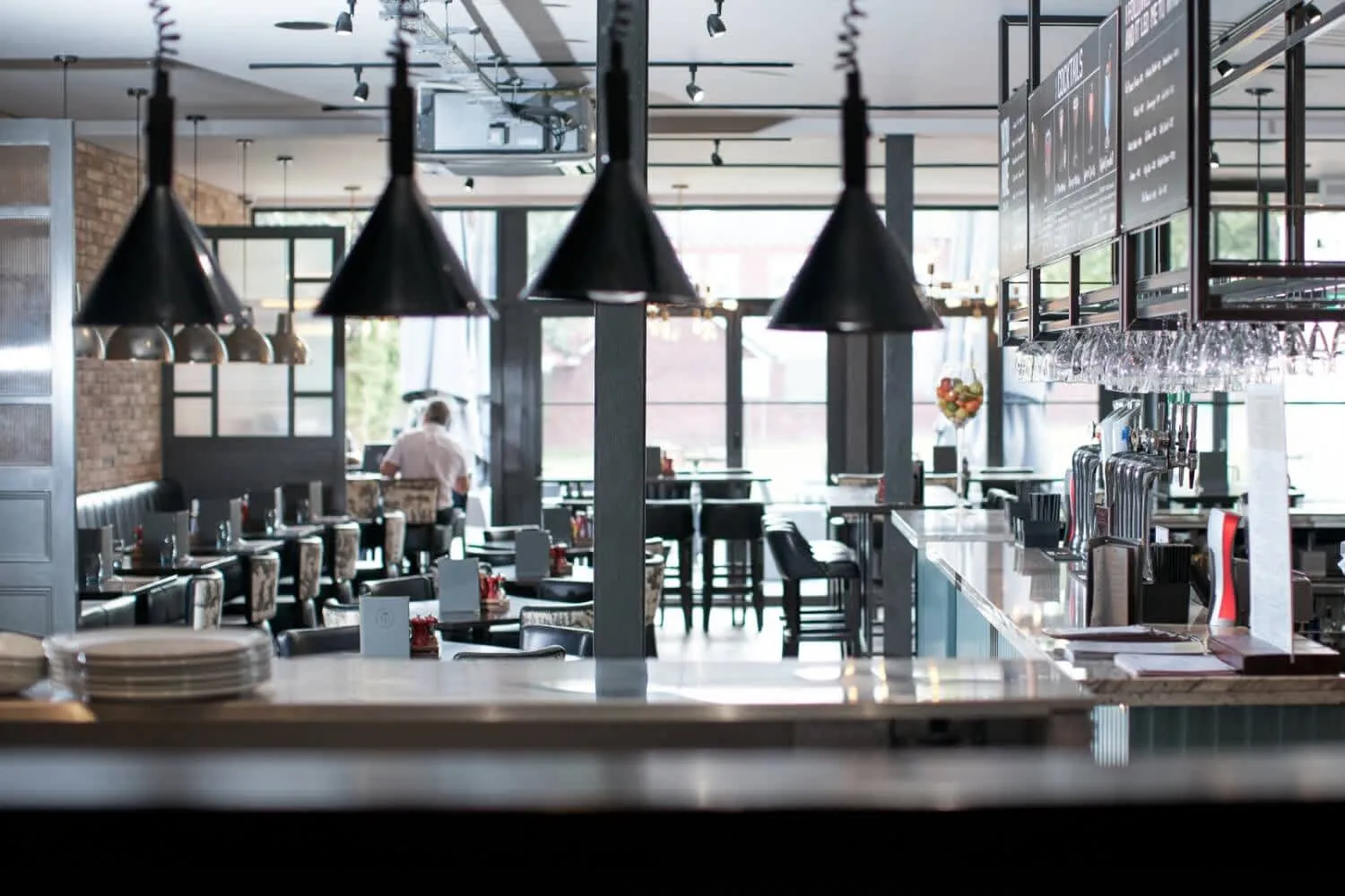 Modern hotel restaurant and bar with black pendant lights, dining tables and beer taps