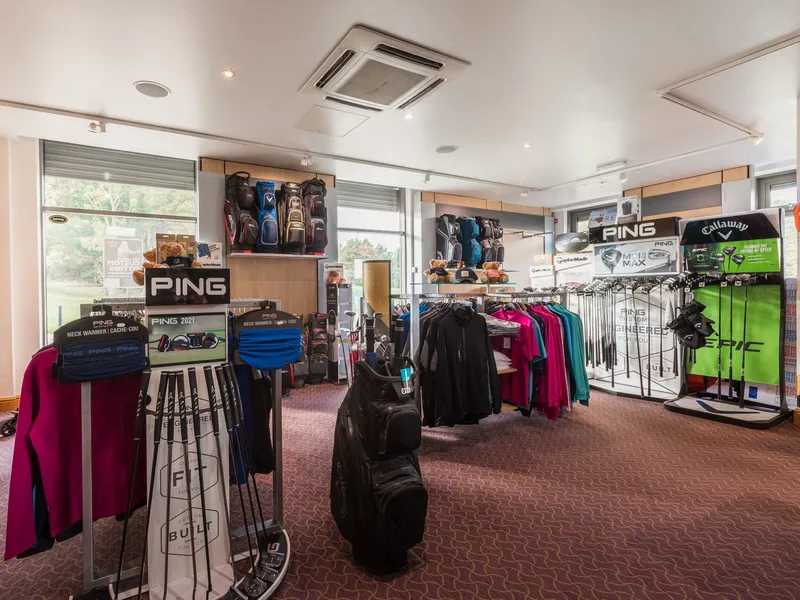 Interior of a golf pro shop displaying golf clubs, bags, clothing and branded accessories.