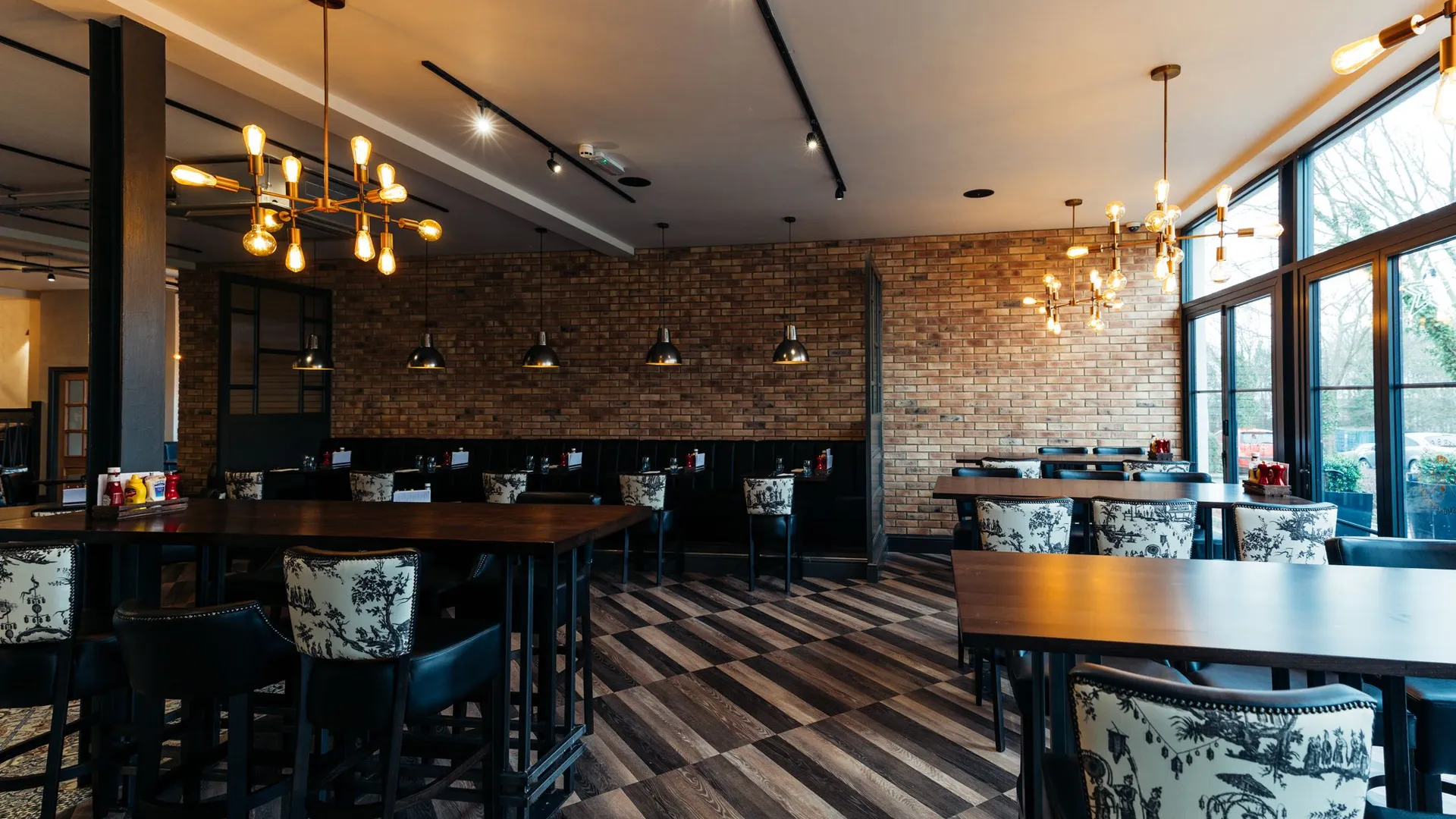 Stylish restaurant dining room with brick walls, dark wood tables and glowing pendant lights