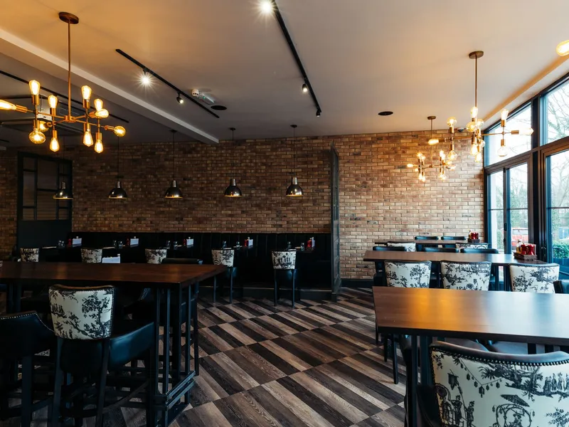 Stylish restaurant dining room with brick walls, dark wood tables and glowing pendant lights