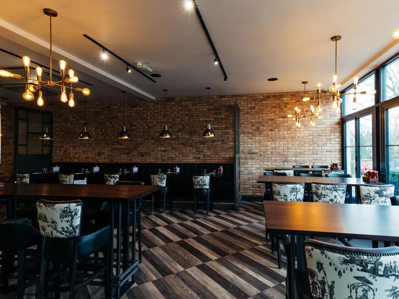 Stylish restaurant dining room with brick walls, dark wood tables and glowing pendant lights