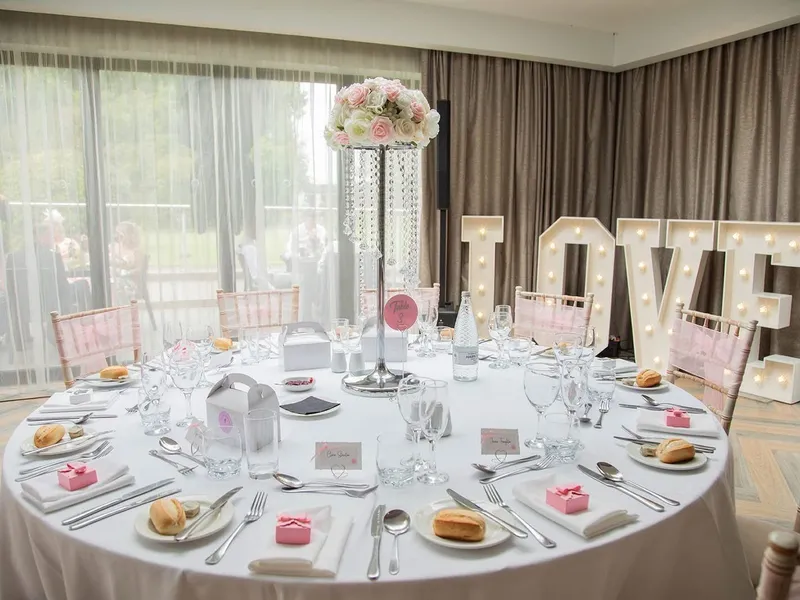 Elegant wedding reception table with rose centrepiece, crystal strands and illuminated LOVE letters