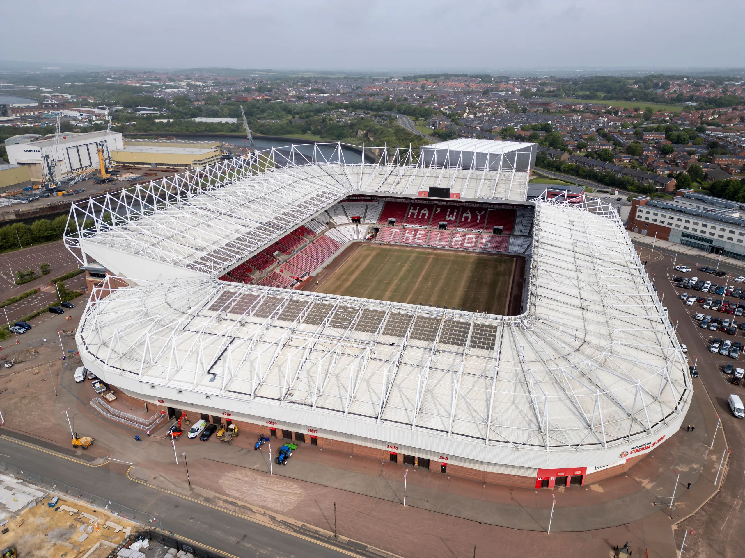 Aerial view of the Stadium of Light football stadium in Sunderland, with red-and-white seating and the surrounding cityscape.