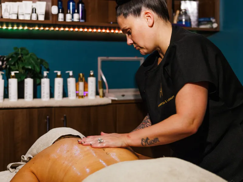 Spa therapist giving a back massage to a client in a treatment room