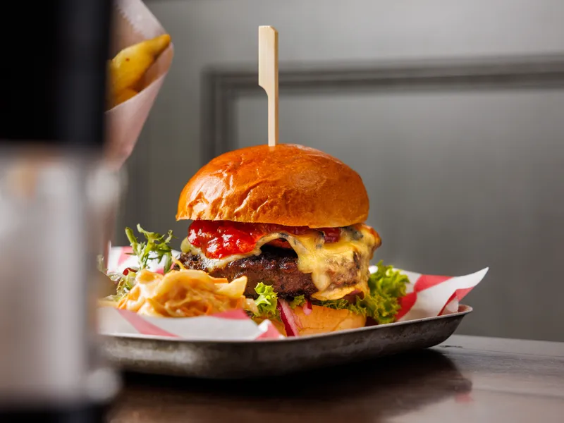 Gourmet cheeseburger with lettuce, red onion and ketchup on a tray in a restaurant