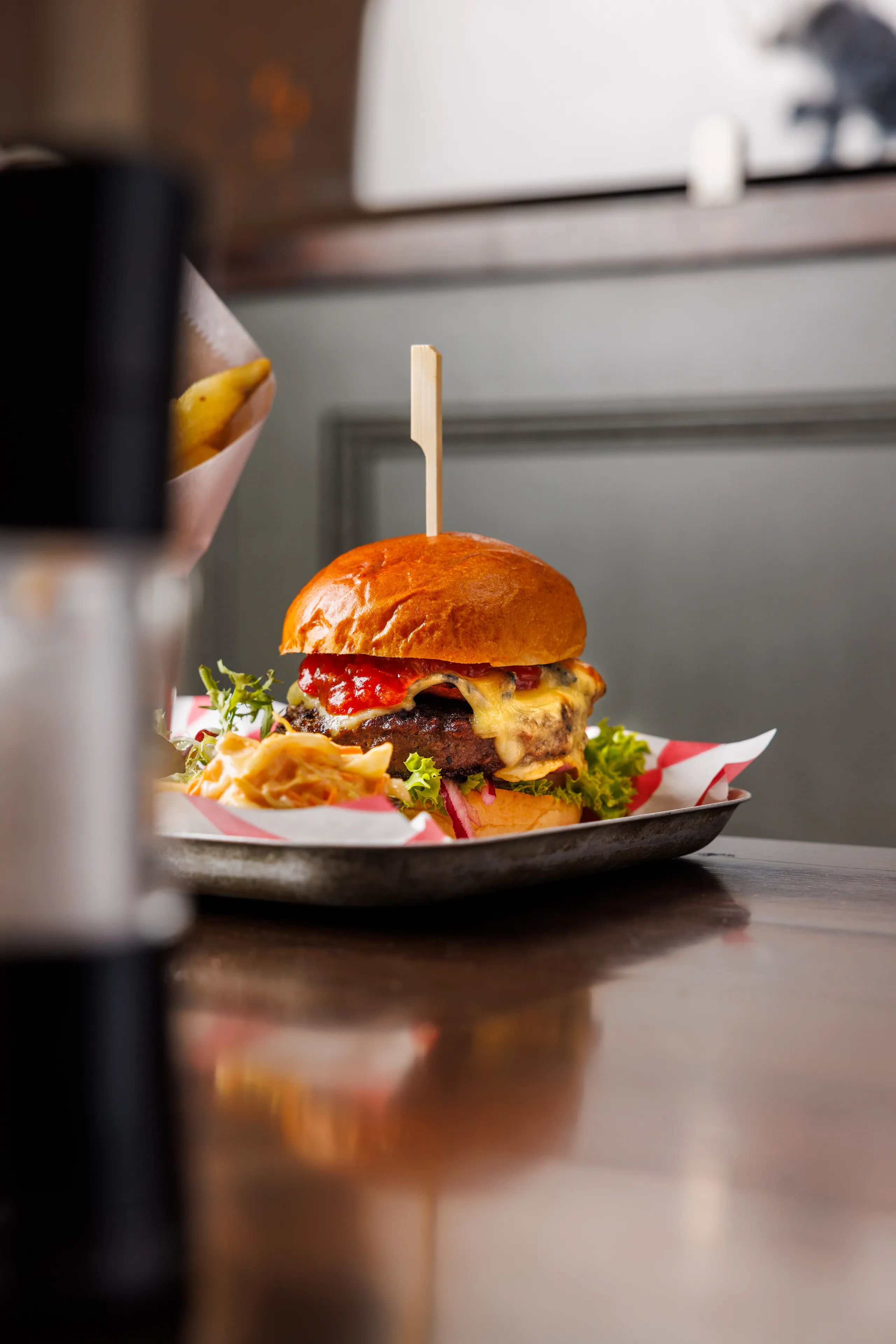 Gourmet cheeseburger with lettuce, red onion and ketchup on a tray in a restaurant