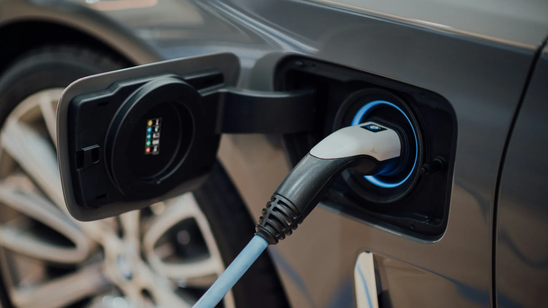 Electric vehicle charging plug connected to a grey car