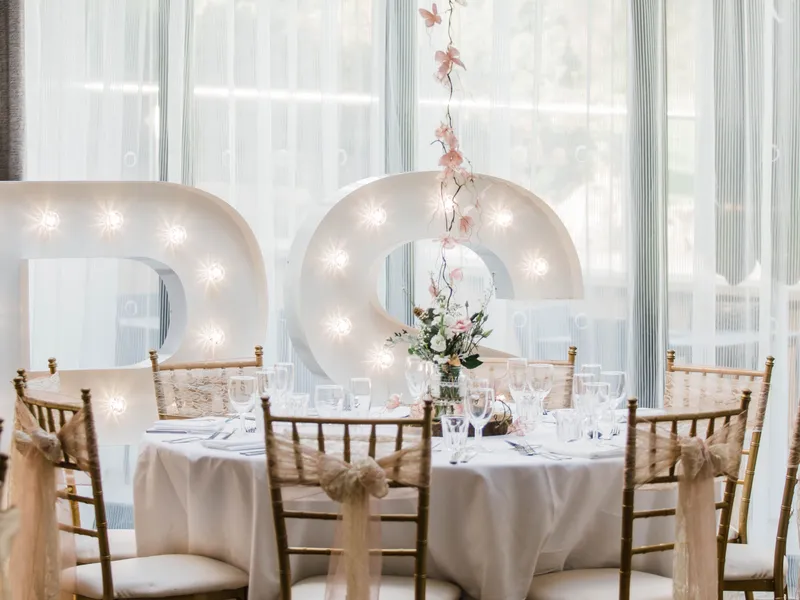 Large white balloon centrepiece above an elegantly dressed wedding table with illuminated love letters